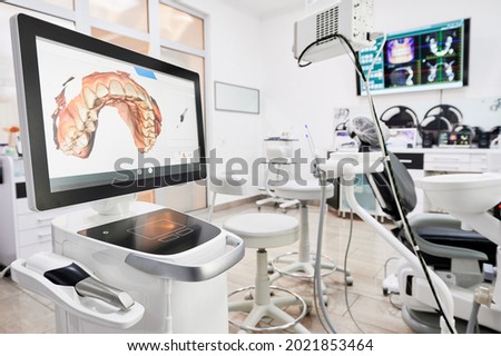 Interior of dental office with modern equipment and dental intraoral scanner with teeth on display, medical system for intraoral scanning. Concept of digital dentistry and dental scanning technology. Royalty-Free Stock Photo #2021853464