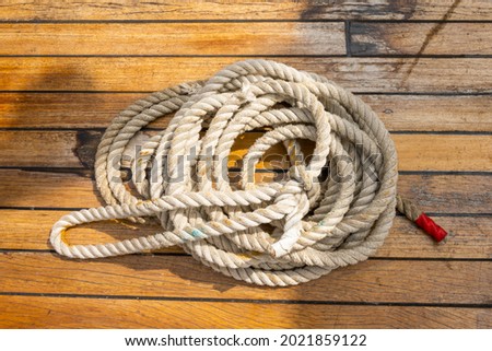 Thick boat rope rolled up on a wooden boat deck. Stock picture to symbolise anything with boats