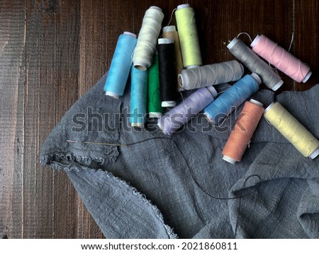 Pastel colour threads on a piece of grey cloth on wooden table
