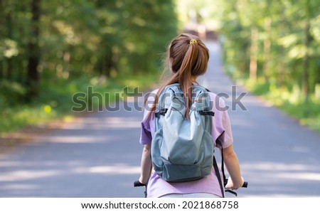 Redhead girl rides a bicycle in a beautiful summer forest. Young woman travels by bike.