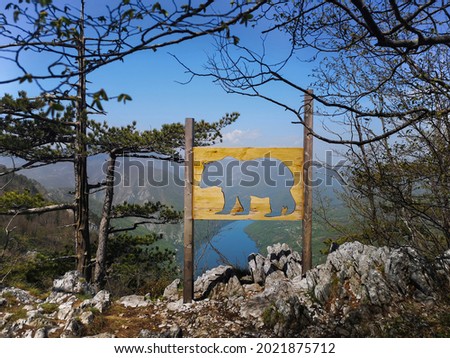Viewpoint Banjska stena with wooden bear sign in Tara national park in Serbia. Popular touristic site, observation point with view over lake Perucac and Drina canyon steep cliffs. Royalty-Free Stock Photo #2021875712