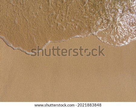 Soft wave on the sandy beach with white clean foam. Space for copy or text. Vacation wallpaper. 