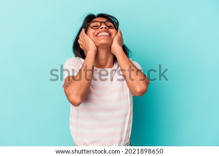 Young latin woman isolated on blue background laughs joyfully keeping hands on head. Happiness concept.