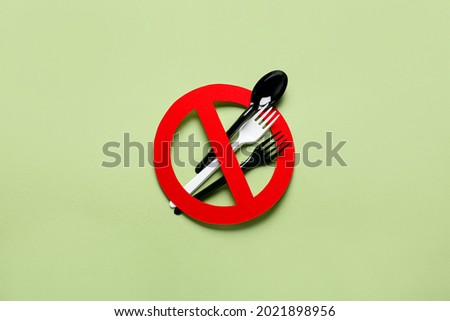 Plastic cutlery with stop sign on color background