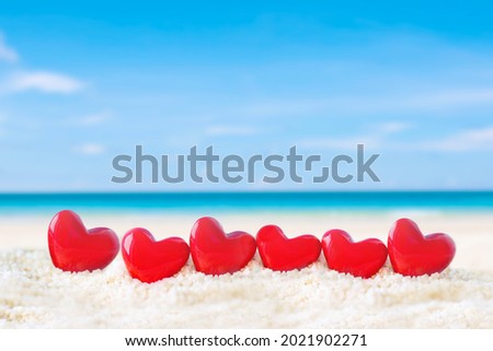 red heart shape on white sand beach 