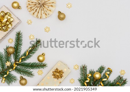 Festive background with gold decoration , green spruce branches and gift boxes ,paper christmas tree decorations, glittering snowflakes and christmas balls