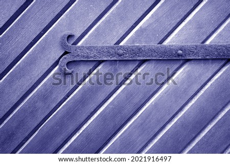 Old metal door hinge on wooden door in blue tone. Abstract background and texture for design.