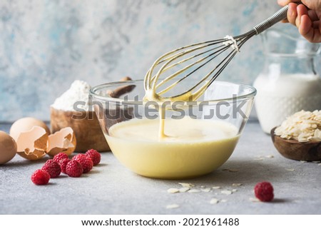 The batter drips off the whisk. Kneading wafer dough. Dough preparation process. Royalty-Free Stock Photo #2021961488