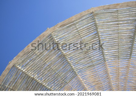 Straw beach umbrella under the sky. Beach sunshade for summer rest. Vacation accessory. Summertime relax. Relaxation equipment. Umbrella and blue sky. straw beach umbrella with blue sky