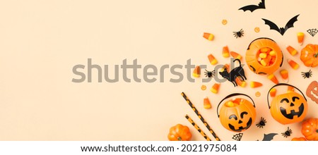 Top view photo of halloween decorations pumpkin baskets candy corn straws spiders web bats and black cat silhouettes on isolated beige background with copyspace