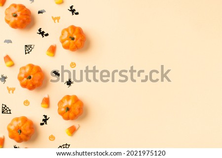 Top view photo of halloween decorations pumpkins candy corn small cats witches spiders web and bats silhouettes on isolated beige background with copyspace