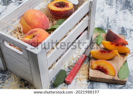 sliced ripe peach and a knife on a cutting board next to a box of peaches