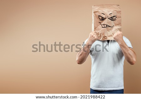 Men put on a paper bag with an angry face painted on it, hold their fists. Isolate on a yellow background, images are easy to crop for use anywhere, copy space