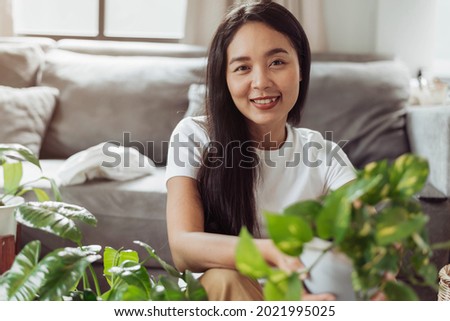 Happy woman sitting with her plants at home. Asian woman gardening at home, Home gardening.