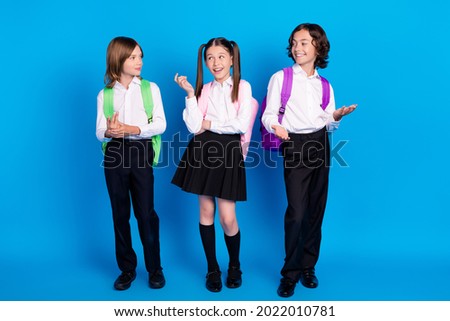 Photo of positive classmates children have conversation wear backpack uniform isolated blue color background