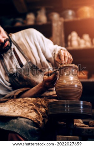 The potter professionally forms the shape of a bowl on a potter wheel from a damp piece of clay Royalty-Free Stock Photo #2022027659