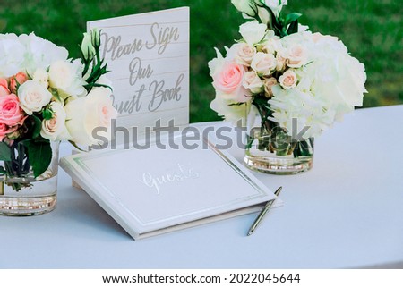 A bouquets of flowers in a vases on a table and a Guest Book