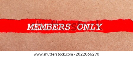 A strip of red paper under the torn brown paper. White lettering on red paper MEMBERS ONLY. View from above