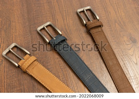 Sueded alligator leather belts colorful on a wooden background for mens fashion.