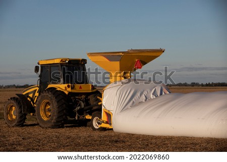 tractor filling silo bags with cattle feed Royalty-Free Stock Photo #2022069860