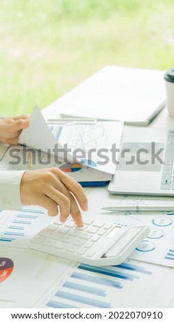 A financial businessman and calculator calculates and analyzes graphs on real estate investment costs and other tax systems. vertical picture picture