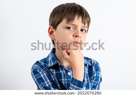 Handsome boy is wearing in plaid shirt thinking about something and puts his hand on the chin. Boy looking away isolated on white background.