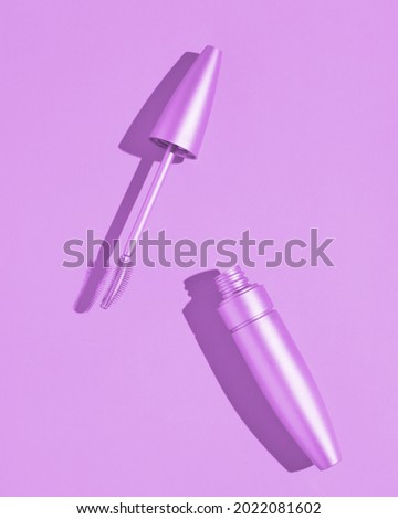 Open tube of mascara. Purple background. Advertising photography aesthetics and minimalism of cosmetics for eyelashes. Fashionable picture with a hard shadow