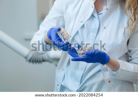 Exhibit of a person's jaw with various defects such as caries and paradanthosis in the hands of dentist