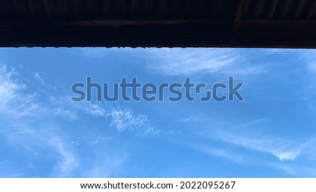 bright blue sky with clouds in summer  At the top of the picture is the roof of the house. Sky background 