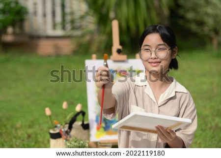 Smiling Asian girl having fun painting with watercolor at the park.