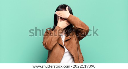 plus size pretty woman covering face with both hands saying no to the camera! refusing pictures or forbidding photos