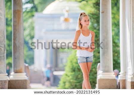 portrait of a slender young teenage girl on the background of antique architecture in the park