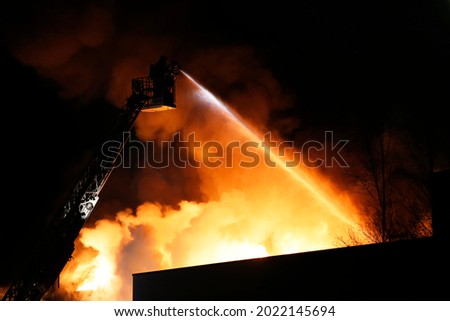 Firefighters using extinguishing water  on a fire in an industrial area