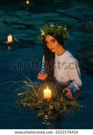 Pagan goddess. water lake, ritual flower wreaths float, candles burning. girl swims in riwer. white vintage shirt Holiday Ivan Kupala. Fantasy woman fortune telling predicts the future magic night.