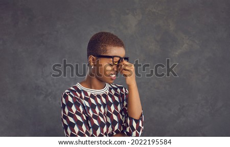 Studio portrait of stressed black lady cringing at mistake or rubbing dry tired eyes and nose bridge. Oh no not again. It's fiasco. I forgot these dumb idiotic hopeless morons make me feel embarrassed Royalty-Free Stock Photo #2022195584