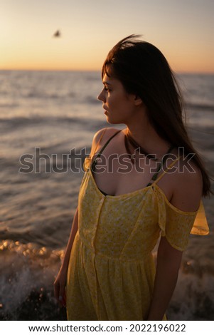 Young woman walks along seashore at sunset. Nature, relax, lifestyle concept.