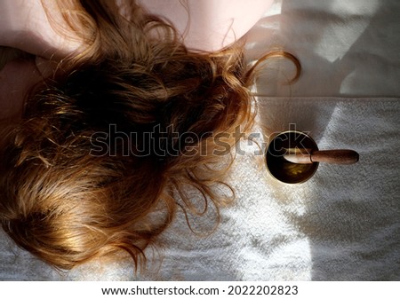 Singing bowl and woman at background in spa salon with sunlight. Sound therapy and body care concept. Top view