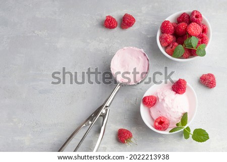 Delicious and romantic dessert. A ball of homemade raspberry walrus with fresh raspberries and mint in a white cup on a light background. Top view. Copy space