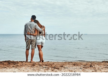 Picture of romantic young couple on the sea shore. Back view. Copy space