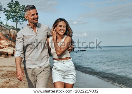 Happy attractive couple walking on beautiful sunny beach. Copy space