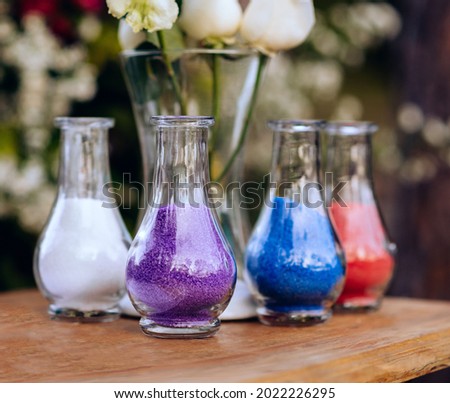 three transparent vases filled with colored sand representing diversity. The sands are white, purple, blue and red