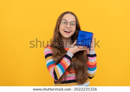 happy teen girl in eyeglasses holding present box for holiday, surprise