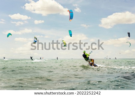 Panoramic view of many people enjoy riding kite surf board in sun uv protection suit on bright sunny day at sea or ocean shore kitesurfing camp spot. Watersport adrenaline fun adventure acitivity Royalty-Free Stock Photo #2022252242