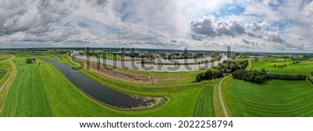 Dutch river IJssel landscape with floodplains and harbor in the background against a blue sky with clouds in The Netherlands. Aerial panorama floodland water management concept. Royalty-Free Stock Photo #2022258794