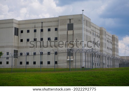A modern correction facility surrounded by a fence and razor wire. Royalty-Free Stock Photo #2022292775