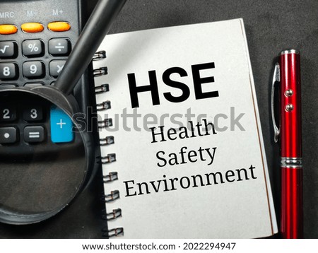 Business concept.Text HSE Health Safety Enviroment writing on notebook with magnifying glass,pen and calculator on a black background.