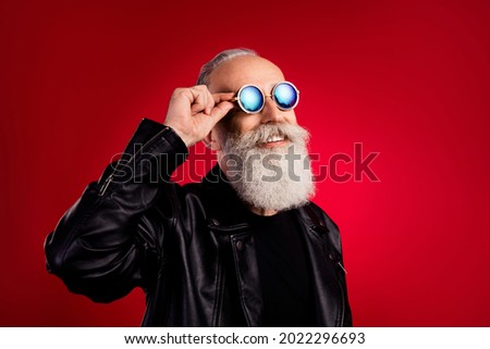 Photo of bearded dreamer old man look empty space wear sunglass leather jacket isolated on red color background