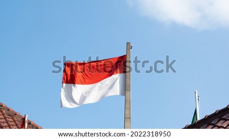 Indonesia national flag waving on the wind against clear blue sky backgroud in the morning

