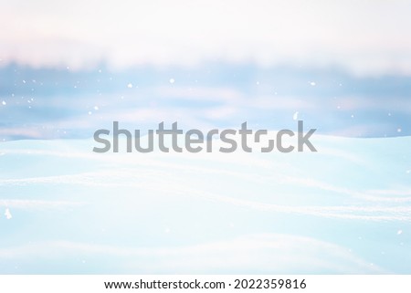 SOFT BLUE BLURRED WINTER LANDSCAPE WITH SNOW AND SNOWFLAKES DURING SNOWFALL, OUTDOOR CHRISTMAS BACKGROUND AT MORNING LIGHT