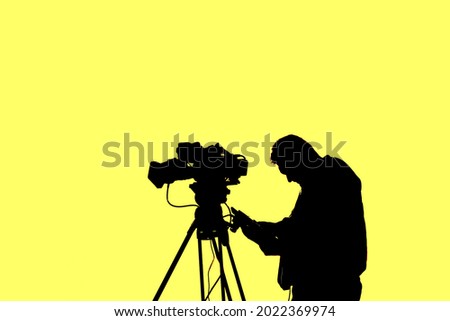 silhouette of Cameraman with professional camera on tripod isolated on white background.